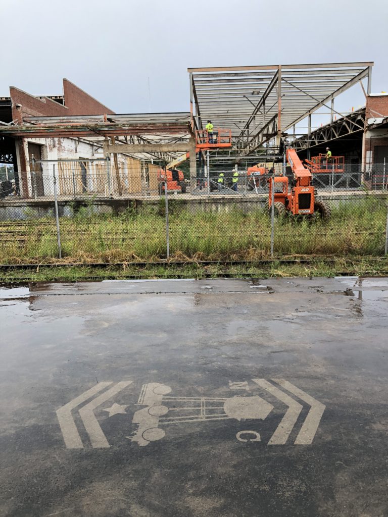 Reverse Graffiti image in the forefront and orange construction trucks in the background