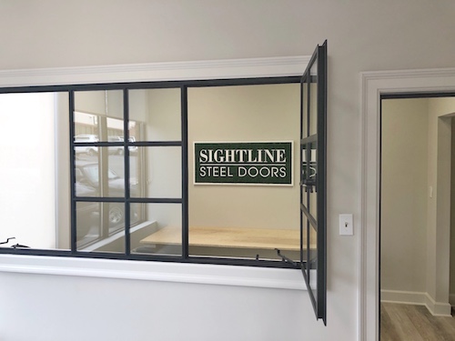 Moss Art sign as seen through a steel framed window in the Sightline Steel Doors showroom.