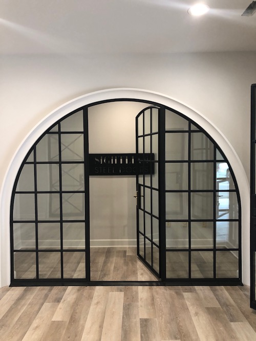 A glass and steel framed door that is perfectly arched.