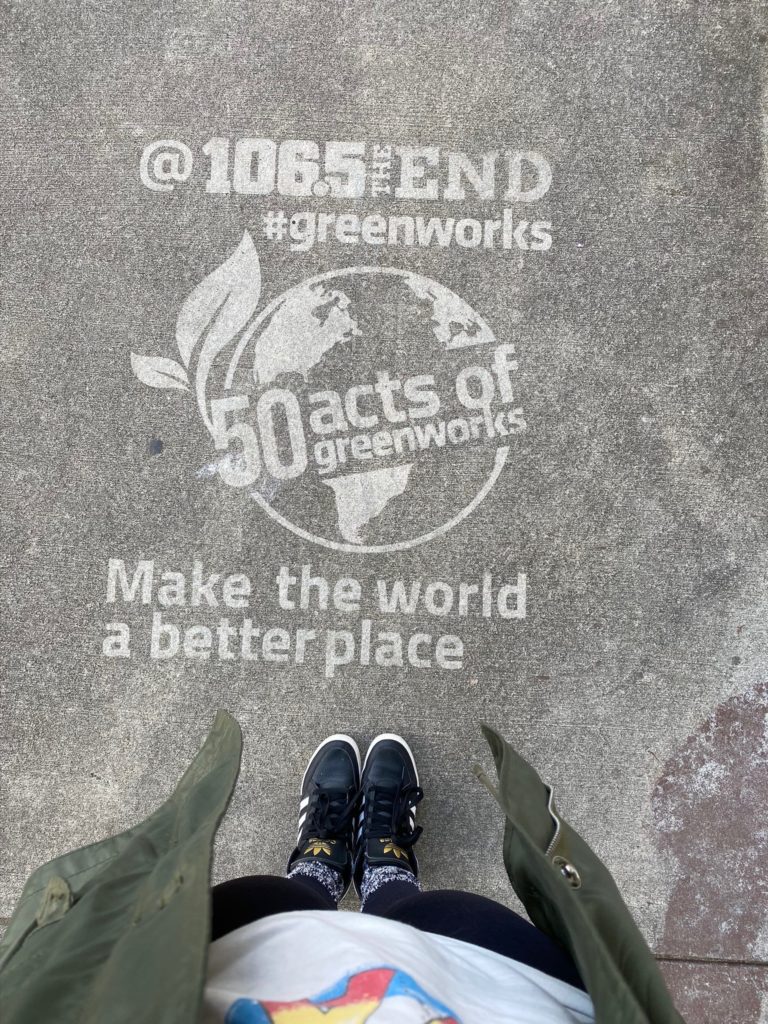 Woman taking a picture of her shoes with a Reverse Graffiti message saying Make the world a better place